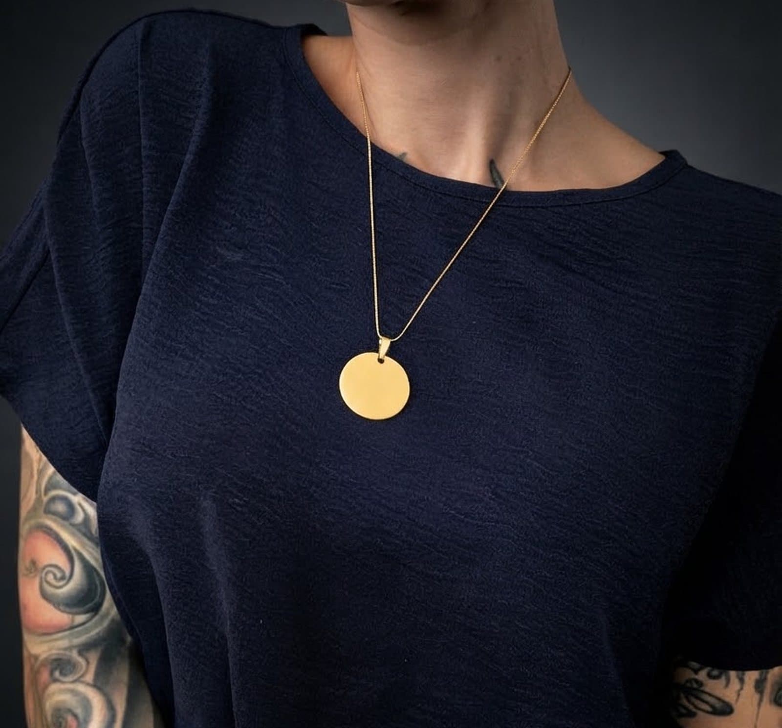 Gold round medallion worn on its snake chain